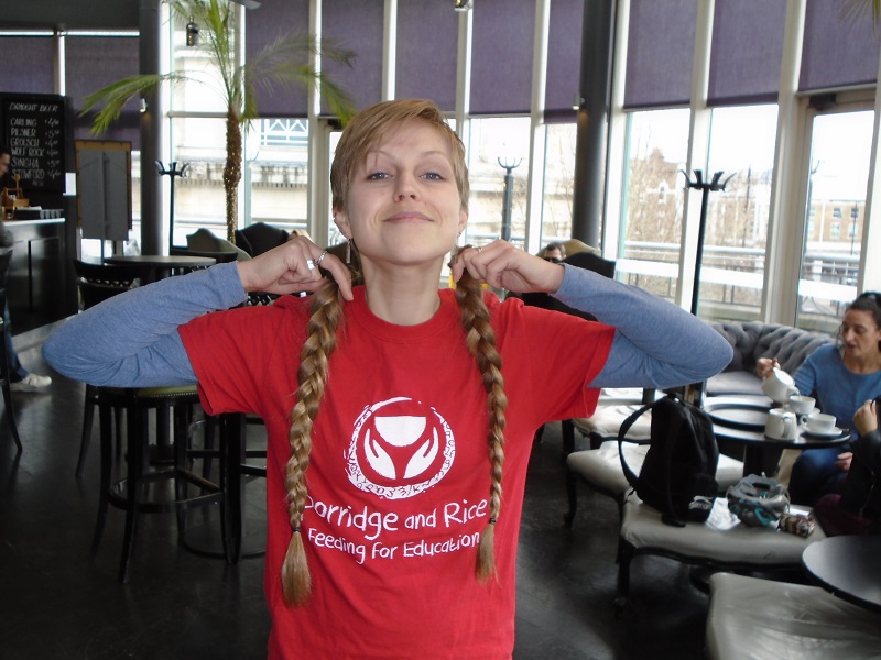 Emma holds up the plaites that have been cut from her head, and which will be sent to a cancer charity
