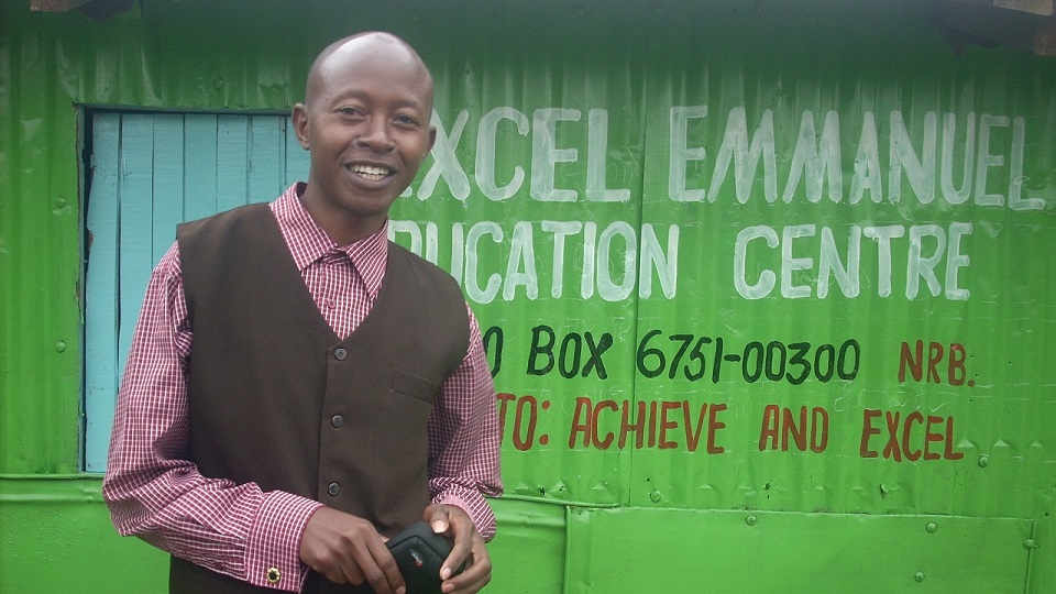 Titus, head teacher of Excel school, outside a newly painted school building 