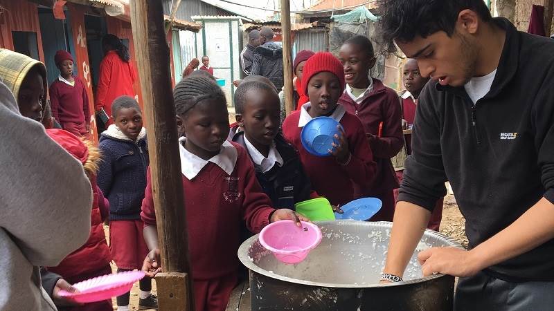 John, a volunteer with Porridge and Rice, helps to serve meals at Lizpal school in Ngando